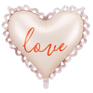 A heart-shaped foil balloon with a soft blush tone and decorative scalloped edges. The word "love" is written in elegant red script across the center. The balloon is isolated on a white background, perfect for romantic or celebratory occasions.
