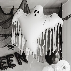 White Halloween ghost balloon with flowing tassels styled in a black and white spooky party display