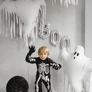 White ghost foil balloon displayed with Halloween decorations and child in skeleton costume