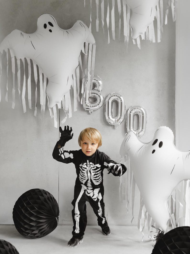 White ghost foil balloon displayed with Halloween decorations and child in skeleton costume