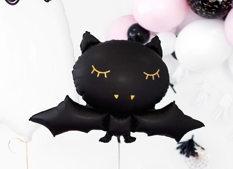 以下が含まれることがあります： 金色のまつげと小さな笑顔をした黒いコウモリの風船。風船は膨らませてあり、ハロウィーンパーティーや飾り付けに使うことができます。
