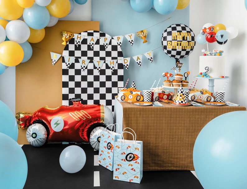 May include: A birthday party table setting with a checkered black and white backdrop. The table is decorated with a checkered tablecloth, red and white checkered paper plates, and red and white checkered cups. There are also red and white checkered party hats, a red and white checkered balloon, and a red and white checkered cake. The table is set for a birthday party with a racing car theme.