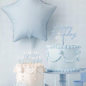 Pastel blue birthday party decoration with star balloon, vintage style birthday cakes, blue cupcakes, and matching plates and candles, perfect for a baby boy's birthday, baby shower, or pastel party theme.