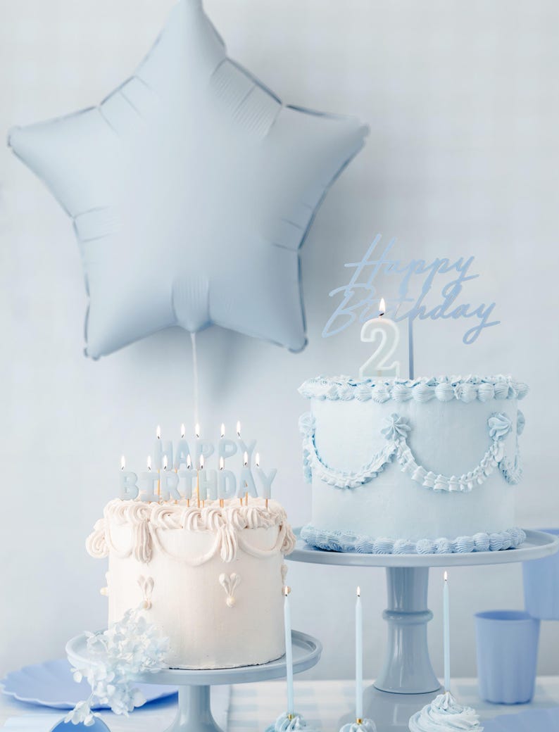 Pastel blue birthday party decoration with star balloon, vintage style birthday cakes, blue cupcakes, and matching plates and candles, perfect for a baby boy's birthday, baby shower, or pastel party theme.