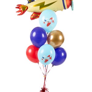 K&ouml;nnte beinhalten: Ein B&uuml;ndel Ballons in Rot, Blau, Gold und Hellblau. Zwei der hellblauen Ballons haben ein kleines Flugzeugmotiv darauf gedruckt. Ein gro&szlig;er gelber Flugzeugballon mit rotem Heck und einem Blitzmotiv befindet sich oben auf dem B&uuml;ndel.