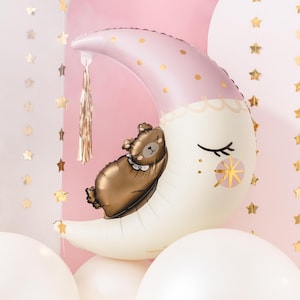 Pu&ograve; includere: Un palloncino a forma di luna crescente rosa e bianco con accenti di glitter dorati e un orso bruno che dorme sopra. Il palloncino &egrave; circondato da palloncini bianchi.