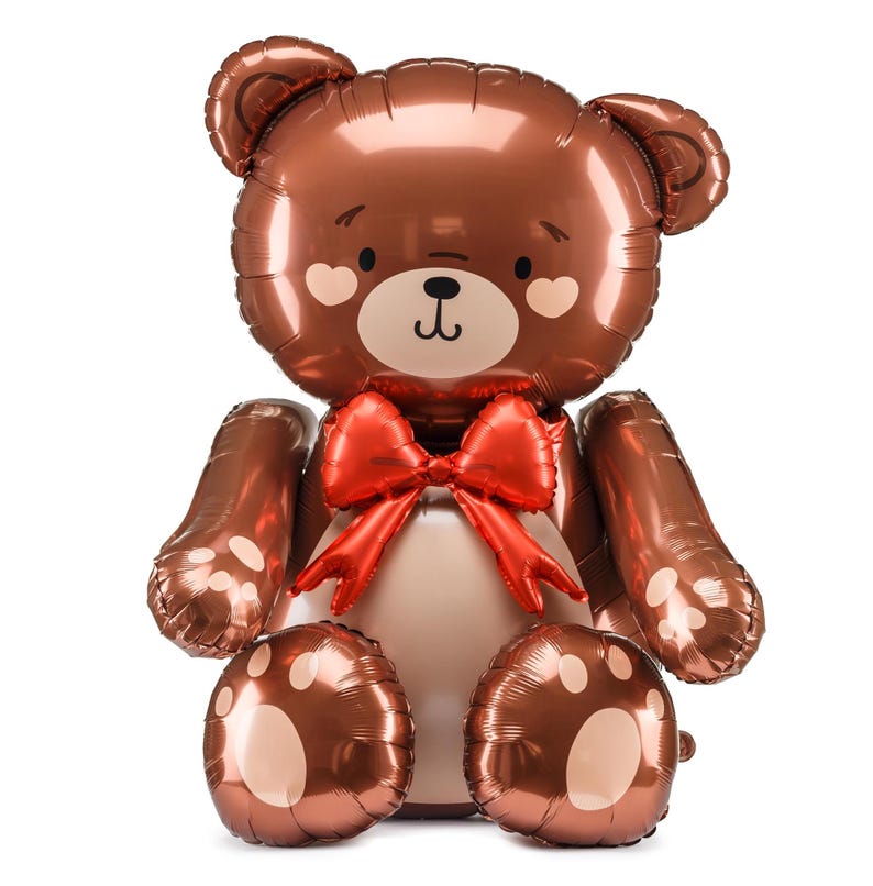 A shiny, metallic brown teddy bear balloon with a cute, smiling face, heart-shaped blush marks on its cheeks, and a large red bow around its neck. The bear is seated with its arms and legs extended, featuring paw print designs on its feet.