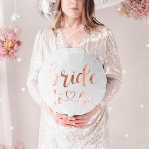 May include: White balloon with the text "bride to be" in rose gold lettering.