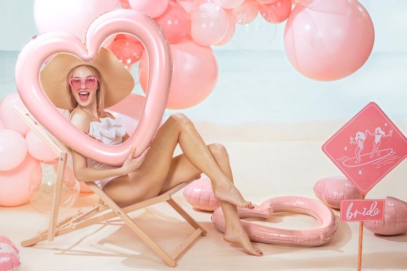 Close-up of a light pink heart balloon frame at a beach party with pink balloon decorations, romantic photo backdrop accessory