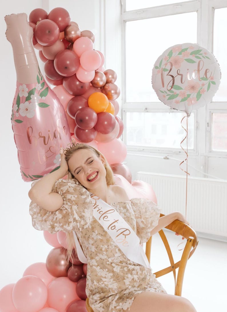 bride to be with rose gold bride balloon, bridal shower decorations with balloon garland, bachelorette party decor setup
