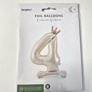 May include: A white foil balloon shaped like the number 4 with a gold crown on top. The balloon is packaged on a white card with the text "FOIL BALLOONS" and "PartyDeco" printed on it. The balloon is 40.5 inches tall and 33 inches wide.