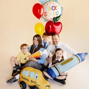 Back to school party with red apple foil balloon, colorful decorations and happy children