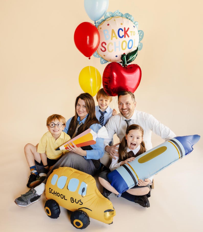 Back to school party with red apple foil balloon, colorful decorations and happy children