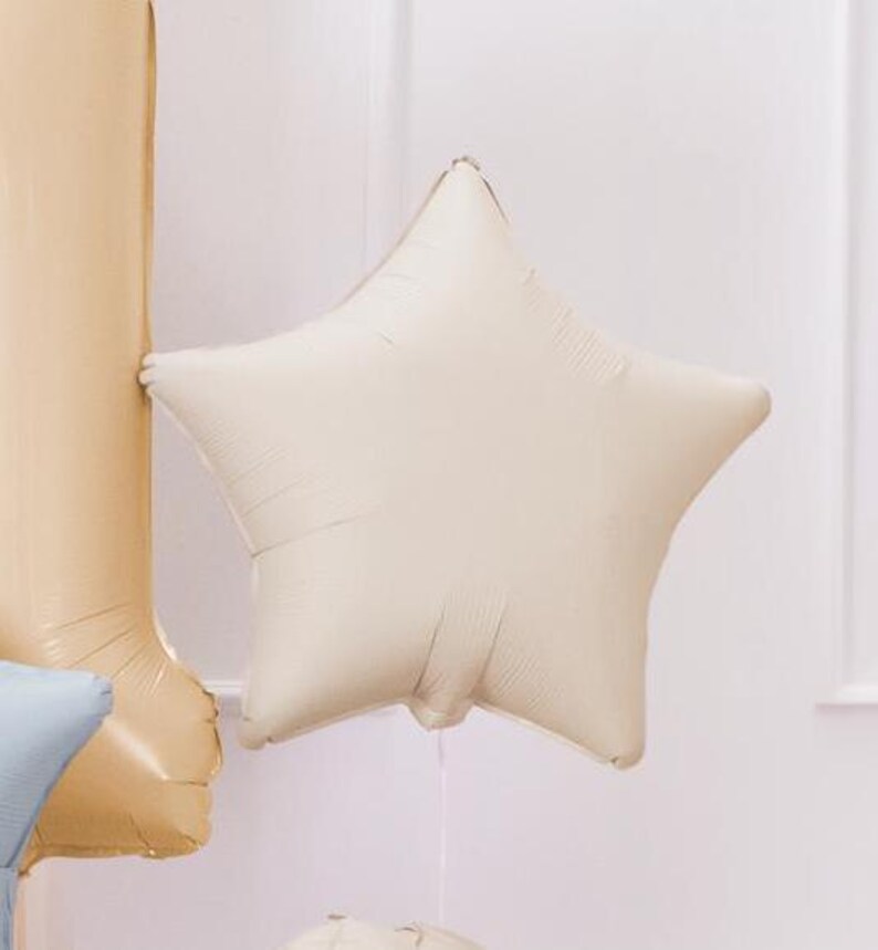 Puede incluir: Un globo de estrella de color crema hecho de papel de aluminio.
