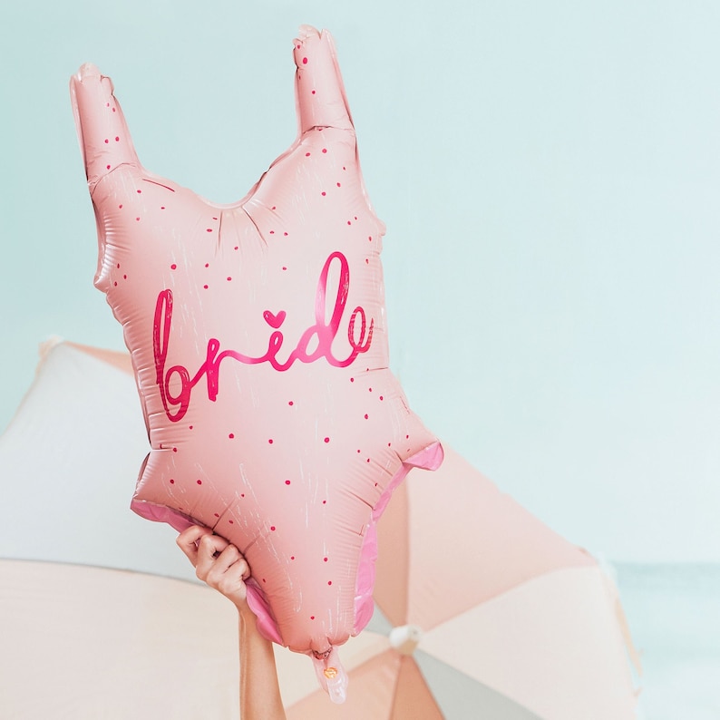 May include: Pink balloon shaped like a dress with the word "bride" in pink lettering and a small heart.