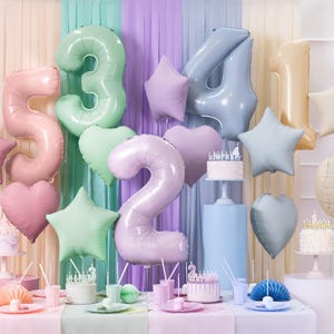 May include: A pastel-colored birthday party decoration set with foil balloons in the shape of numbers 1, 2, 3, 4, and 5, stars, and hearts. The balloons are arranged in front of a backdrop of pastel-colored streamers.