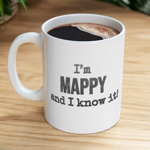 May include: White ceramic coffee mug with a black handle. The mug has black text that reads "I'm MAPPY and I know it!"
