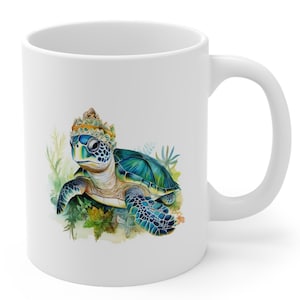 May include: White ceramic mug featuring a colourful illustration of a sea turtle wearing a gold crown. The turtle is surrounded by green and blue watercolour foliage.