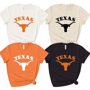 May include: Four t-shirts with the word "TEXAS" and a stylized Longhorn steer logo. The shirts are in white, beige, orange, and black.