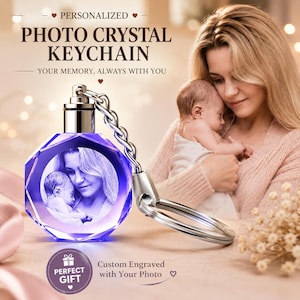 Puede incluir: Un llavero de cristal circular facetado con una fotografía monocromática grabada con láser de una persona sosteniendo a un bebé. El cristal tiene un tono púrpura y está unido a una cadena y anilla de metal plateado. Texto: PERSONALIZED PHOTO CRYSTAL KEYCHAIN.