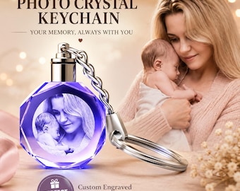 May include: A faceted, circular crystal keychain featuring a laser-engraved monochrome photograph of a person holding a baby. The crystal has a purple tint and is attached to a silver-toned metal chain and ring. Text reads: PERSONALIZED PHOTO CRYSTAL KEYCHAIN.