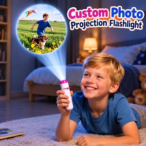 May include: A white handheld flashlight with a pink top and switch that projects a circular image of a child running with a dog and a kite. The text Custom Photo Projection Flashlight is displayed in blue and pink letters above the projection.