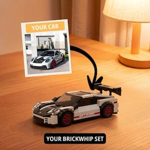 May include: A white and black toy car with red wheels and a rear spoiler. The car has the text "GTS 3.8" on the side. A photo of a real car is attached to the toy car with a black arrow. The photo has the text "YOUR CAR". The text "YOUR BRICKWHIP SET" is below the toy car.