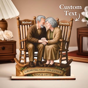 Puede incluir: Figura de madera que representa a una pareja de ancianos tomados de la mano en mecedoras. Las sillas están grabadas con los nombres "Michael" y "Amanda". La base dice "Growing Old Together Since 1975."
