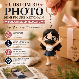 Peut inclure: Un porte-clés personnalisé avec photo 3D représentant une figurine. La figurine de dessin animé a des cheveux noirs, un haut blanc et une jupe bleue, portant un masque noir. Le porte-clés est attaché à une chaîne argentée. Le texte sur l'image indique "Souvenir personnalisé."