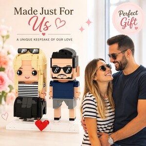 May include: Two custom block-style figures resembling a couple, one with blonde hair and a striped shirt, the other with dark hair and a blue shirt, standing on a white base with a red heart. Text reads: Made Just For Us, A UNIQUE KEEPSAKE OF OUR LOVE.