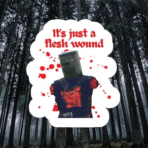 May include: A sticker featuring a knight in black armor with the text "It's just a flesh wound" in red. The knight is missing both arms, with red blood splatters around the image. The background is a forest.