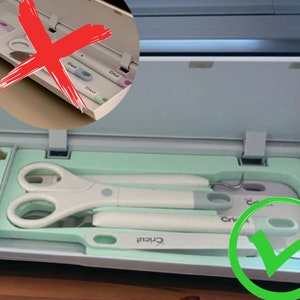 Op de afbeelding: Een close-up van het gereedschapsvak van een Cricut-machine. Het vak is open en bevat een verscheidenheid aan gereedschap, waaronder een schaar, een onkruidverwijderingsgereedschap en een schraper. De gereedschappen zijn netjes in het vak gerangschikt. Een rood kruis is getekend over het bovenste vak, terwijl een groen vinkje is getekend over het onderste vak.