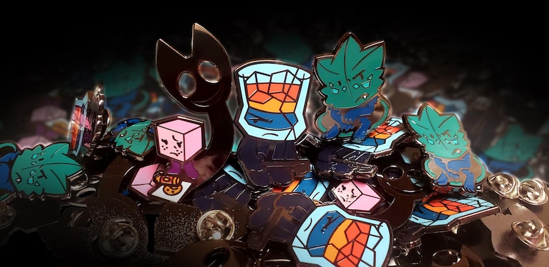 Puede incluir: Una colecci&oacute;n de pines de esmalte met&aacute;lico con varios dise&ntilde;os, incluyendo una criatura de silueta oscura, un personaje de cubo rosa, un vaso lleno de l&iacute;quido naranja y azul, y una criatura verde azulada con detalles en azul, con cierres.