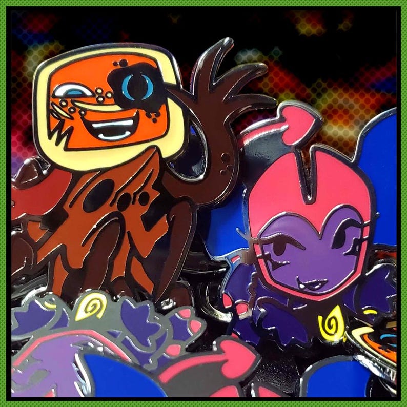 May include: Enamel pin featuring two cartoon characters. One is orange with a TV-shaped head, the other is purple with a pink head and blue wings. The background is a mix of red, yellow, and black.