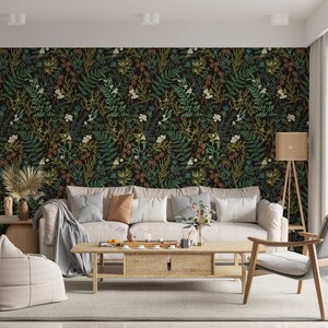 Puede incluir: Un interior de sala de estar con un sof&aacute; blanco y una mesa de caf&eacute;. La pared est&aacute; cubierta con un papel tapiz floral verde oscuro y marr&oacute;n con un patr&oacute;n repetitivo de hojas y flores.