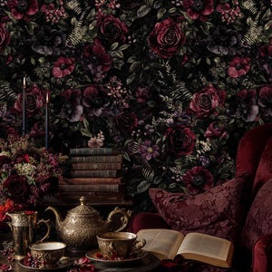 May include: A dark, moody interior scene featuring a floral wallpaper with deep red and purple roses. A gold tea set, books, and a red armchair create a vintage aesthetic. Two lit candles add a touch of elegance.
