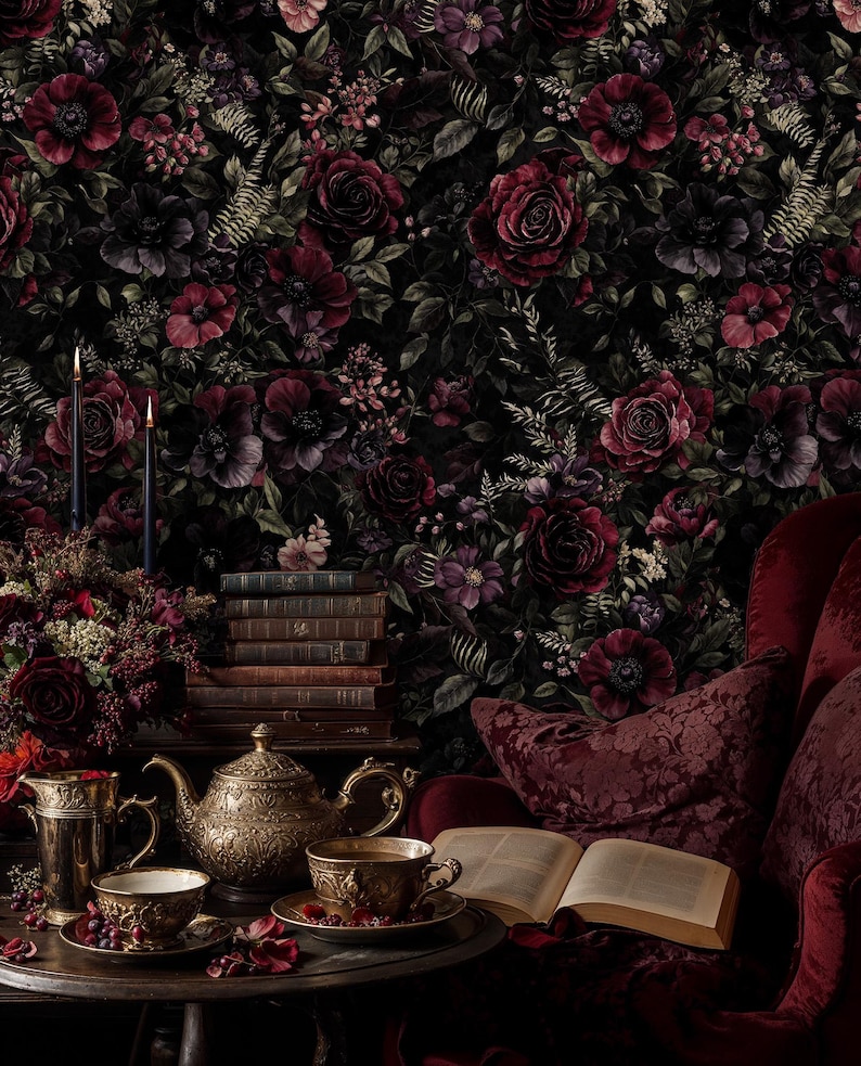 May include: A dark, moody interior scene featuring a floral wallpaper with deep red and purple roses. A gold tea set, books, and a red armchair create a vintage aesthetic. Two lit candles add a touch of elegance.