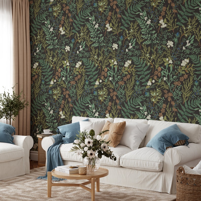 Puede incluir: Un sof&aacute; blanco con cojines azules y un arreglo floral en un jarr&oacute;n transparente se encuentra frente a un papel tapiz verde oscuro con un patr&oacute;n floral.