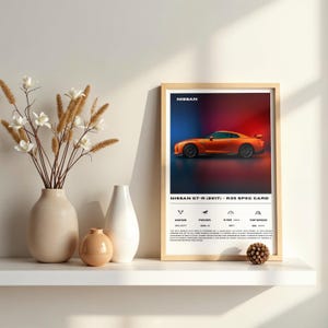 Puede incluir: Un póster enmarcado con un coche deportivo Nissan GT-R naranja. El póster incluye las especificaciones del coche y la palabra "NISSAN" en la parte superior. El fondo es un degradado de rojo y azul.