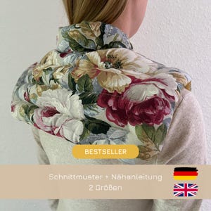 Puede incluir: Un protector de cuello con un estampado floral de grandes rosas rojas, blancas y amarillas sobre un fondo claro. El texto BESTSELLER aparece en un recuadro amarillo, seguido de indicaciones sobre un patrón de costura e instrucciones en dos tallas.