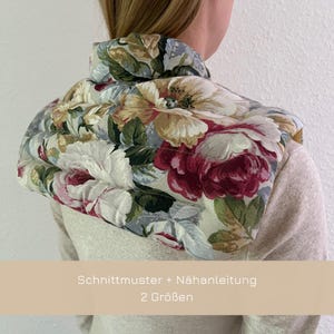 Könnte beinhalten: Ein Nackenwärmer mit floralem Muster und gestepptem Design. Der Text "Schnittmuster + Nähanleitung 2 Größen" ist auf einem beigefarbenen Hintergrund gedruckt.