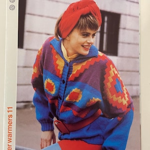 Op de afbeelding: Een vrouw draagt een blauwe, rode, gele en paarse geruite cardigan met een rode riem en een rode tulband. De cardigan heeft een knoopsluiting. De afbeelding is afkomstig uit een breipatronenboek getiteld "Winter Warmers 11".
