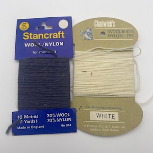 Może przedstawiać: Dwa szpulki nici, jedna granatowa, a druga biała. Granatowa szpulka jest oznaczona "Stancraft Wool/Nylon" i ma napis "30% Wool 70% Nylon No 814" na dole. Biała szpulka jest oznaczona "Chadwick's Wool & 85% Nylon 15%" i ma napis "For reinforcing and mending White A Product of J. & P. Coats Ltd. Made in Great Britain" na dole.