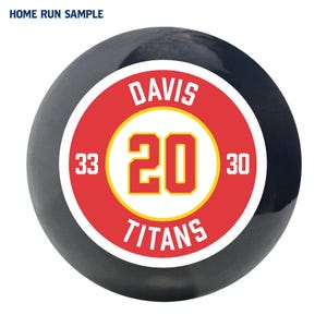 May include: A black and red baseball with the text "DAVIS 20 TITANS" in white and yellow lettering. The numbers "33" and "30" are on either side of the number "20".