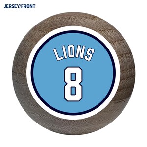 May include: A light blue and white baseball jersey with the word "LIONS" and the number "8" on the front.