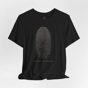 May include: Black t-shirt featuring a fingerprint design in a light beige color. The shirt has the text "RETURN TO SOURCE" printed below the fingerprint. The t-shirt is made of a soft material.