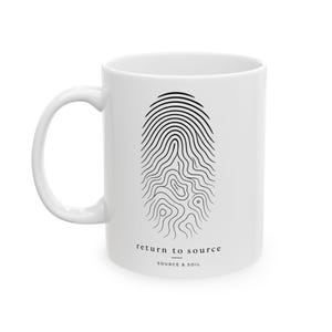 May include: White ceramic mug featuring a black fingerprint design. The mug has the text "return to source" and "source & soil" printed in black. The mug has a curved handle and a smooth, glossy finish.