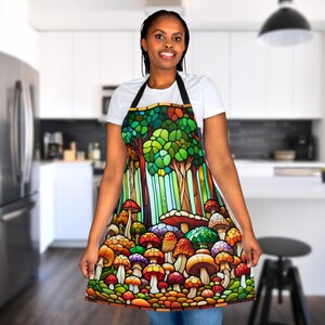 May include: A colorful kitchen apron with a stained glass design of mushrooms and trees. The apron is black with a green, blue, red, orange, and yellow design.