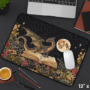 May include: A black and gold dragon with wings outstretched sits on top of an open book. The dragon is surrounded by flowers and stars on a black background. The book is open to a page with text. The mousepad is 30.5 cm by 45.7 cm.