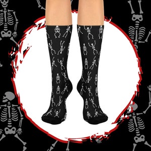 May include: A pair of black socks with a white skeleton pattern. The skeletons are dancing and have a fun, whimsical look.